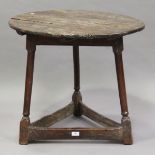 An 18th century oak circular cricket table, on three outswept turned legs united by block