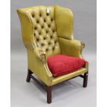 A 20th century George III style buttoned green leather wingback armchair, on moulded block legs,