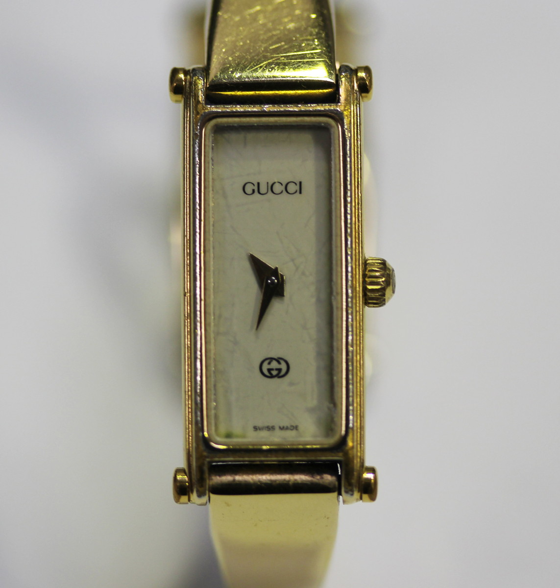 A Gucci gilt metal lady's bangle wristwatch with signed rectangular cream coloured dial, case