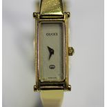 A Gucci gilt metal lady's bangle wristwatch with signed rectangular cream coloured dial, case