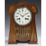 An Art Nouveau inlaid mahogany cased mantel clock with eight day movement striking on a gong, the