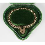 A gold decorated and plain hollow curblink bracelet on a gold heart shaped padlock clasp with
