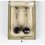 A pair of diamond and onyx pendant earrings, each faceted onyx bead with a diamond set collar and