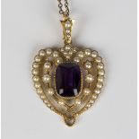 A gold, amethyst and seed pearl pendant, circa 1910, in a pierced openwork stylized heart shaped