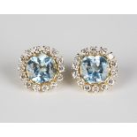 A pair of gold, blue topaz and diamond set earstuds, each mounted with a cushion cut blue topaz