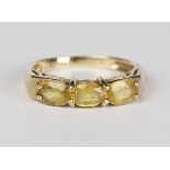 A 9ct gold and yellow gemstone set three stone ring, mounted with a row of three oval cut yellow