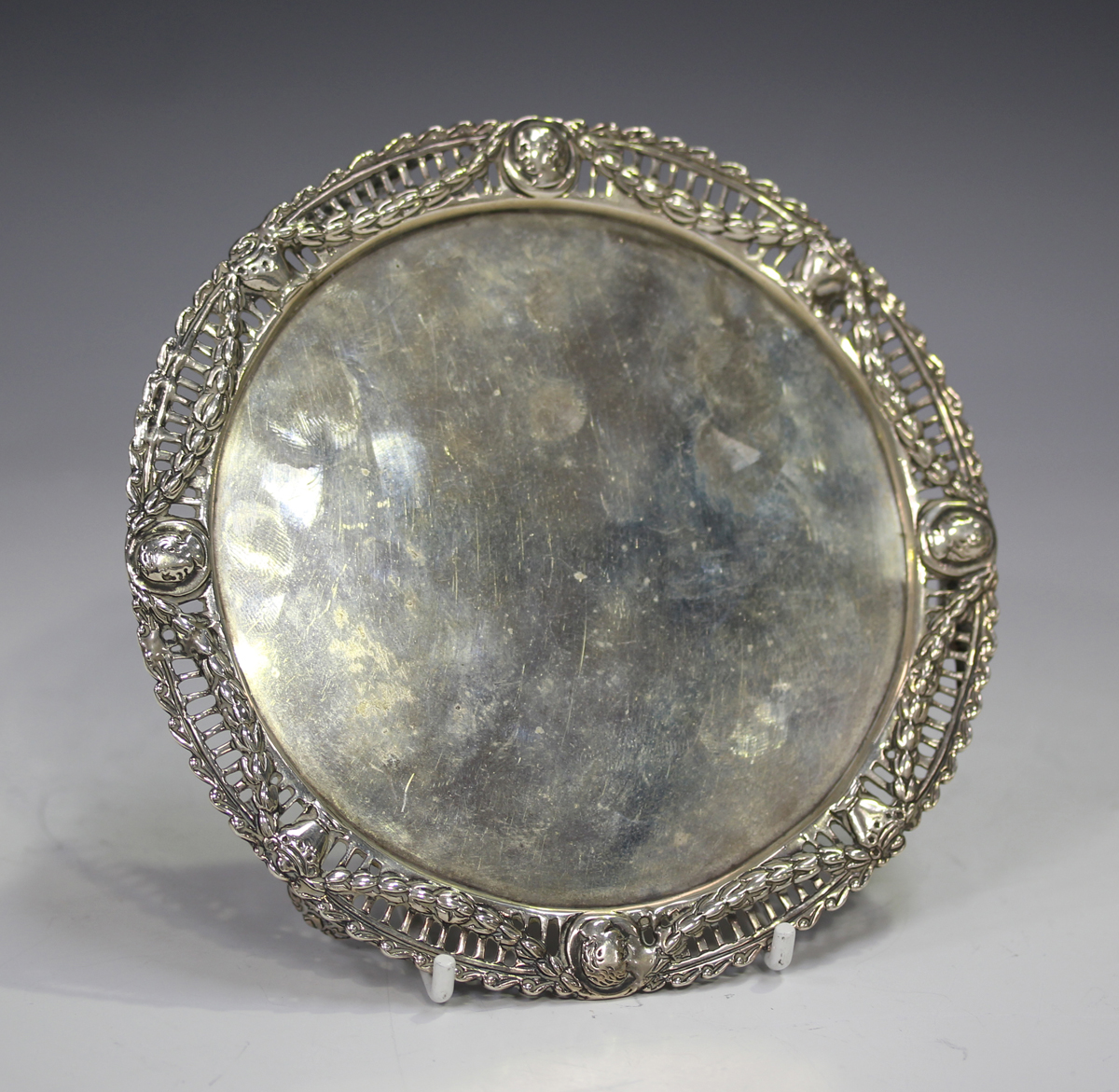 A late Victorian silver circular card salver, the cast rim pierced with portrait bust panels and