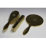 An Edwardian silver gilt three-piece dressing table set, comprising hand mirror, hairbrush and