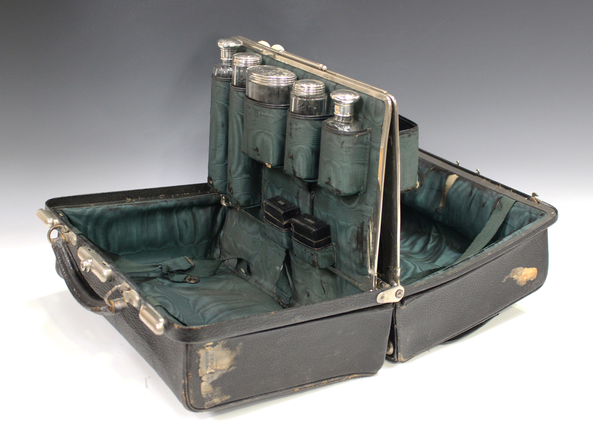 An Edwardian black leather Gladstone vanity bag, the interior fitted with five silver and cut