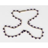 An amethyst necklace, claw set with a row of circular cut amethysts, on a cylindrical clasp,