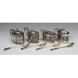 A group of four George V silver mustards, each with hinged lid, blue glass liner and pierced
