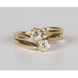 A gold and diamond two stone ring, mounted with cushion cut diamonds in a cross-over design,