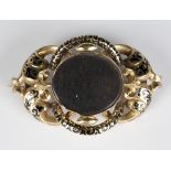 A Victorian gold and black enamelled shaped oval mourning brooch, circa 1860, glazed with a locket