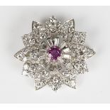 A white gold, diamond and ruby brooch in a floral shaped design, claw set with a central circular