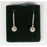A pair of white gold and diamond pendant earrings, each claw set with a row of circular cut diamonds