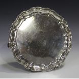 A George V silver circular card salver with piecrust rim, on scroll feet, Sheffield 1920 by Martin