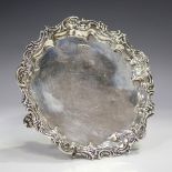 A George V silver circular card salver with cast foliate scroll rim, raised on scroll feet,