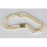 A three row necklace of cultured pearls on a 9ct gold, amethyst and cultured pearl cluster clasp,