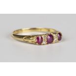 An 18ct gold, ruby and diamond ring, mounted with three cushion cut rubies alternating with two