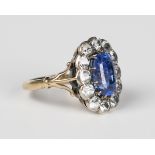 A sapphire and colourless gem set oval cluster ring, claw set with the oval cut sapphire within a