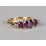 An 18ct gold, ruby and diamond ring, mounted with three circular cut rubies graduating to the centre