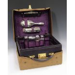 A George V leather vanity case, the fitted interior containing silver mounted dressing table