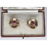 A pair of 9ct gold and ruby earclips, each designed as a stylized flowerhead, London 1953,