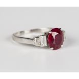 A ruby and diamond ring, claw set with an oval cut ruby between baguette cut diamond graduated two