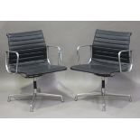 A pair of EA 108 cast aluminium and black leather revolving armchairs, made by Vitra and designed by