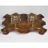 An early 20th century mahogany and satinwood inkstand, fitted with two glass inkwells on a