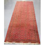 An Afghan runner, late 20th century, the red field with overall columns of guls, within a striped