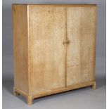 An early 20th century limed oak compactum wardrobe, in the manner of Heals, the two doors