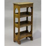 An early 20th century Arts and Crafts style oak open bookcase with a stop-fluted frieze and arched