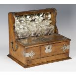 An Edwardian oak and plate mounted three-bottle tantalus, the double-hinged compartment above a
