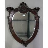 An Edwardian mahogany wall mirror of cartouche form, the foliate carved frame with three small