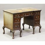 A George V mahogany inverted breakfront writing desk, the top inset with leather above an