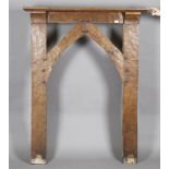 An early 20th century Arts and Crafts oak fire surround, the arched frame with pegged joints and