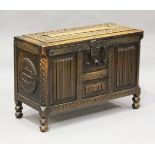 An early 20th century Arts and Crafts style carved walnut coffer, the hinged lid and front with a