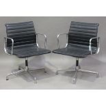 A pair of EA 108 cast aluminium and black leather revolving armchairs, made by Vitra and designed by