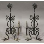 A pair of early 20th century Arts and Crafts wrought iron fire andirons, each spiral ovoid finial