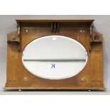 An Edwardian Arts and Crafts oak overmantel mirror, in the manner of Shapland & Petter, the oval