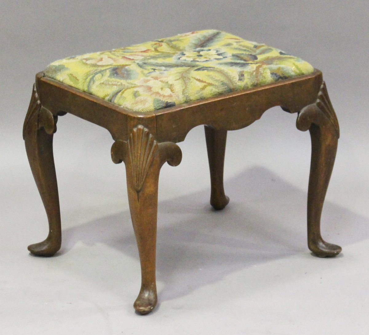 An early 20th century Queen Anne style walnut stool, the drop-in woolwork seat on scallop shell