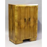 An Art Deco walnut bedroom cabinet with angular edges and Bakelite handles, height 122cm, width