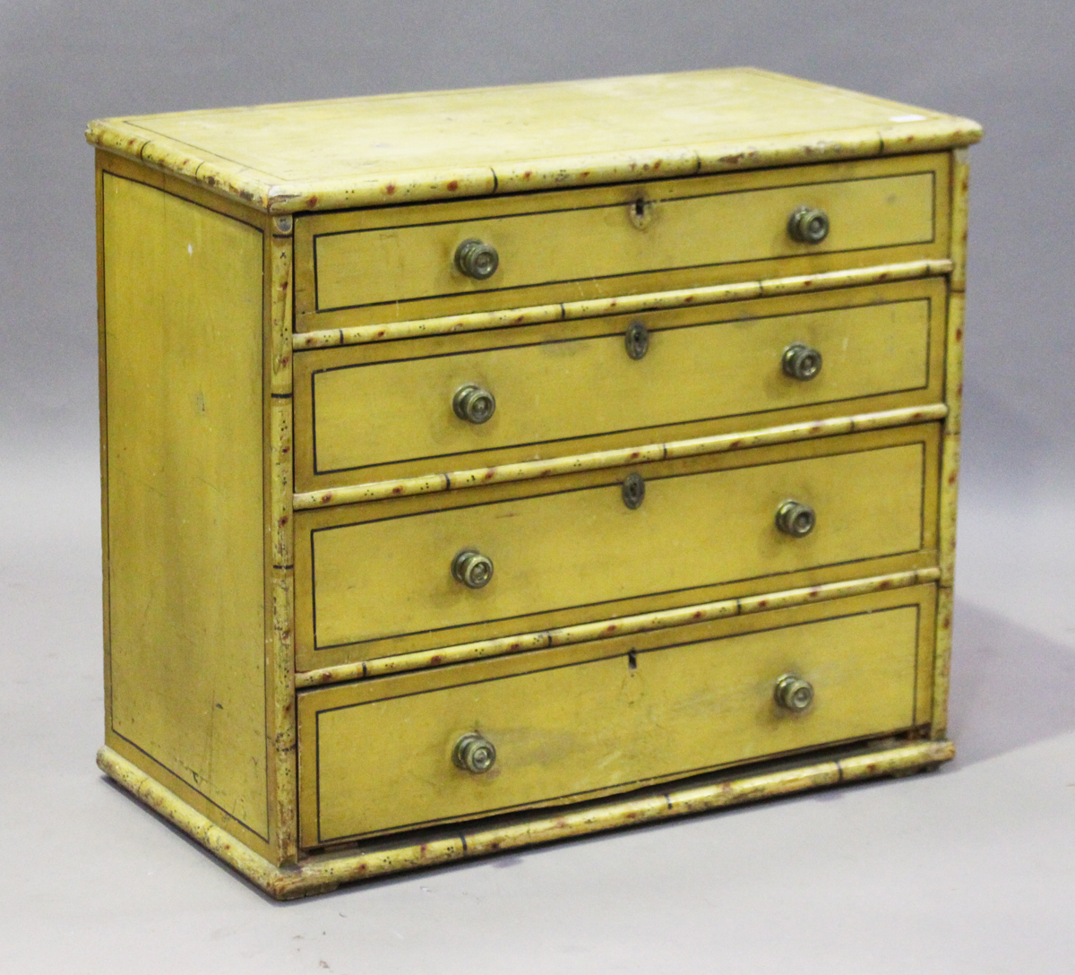 A Regency painted pine chest of four graduated long drawers with faux bamboo edging and black