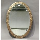 An early 20th century Arts and Crafts oval copper wall mirror with hammered decoration, 85cm x