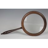 A 19th century rosewood gallery glass, the large circular frame supporting a glass lens, length 45.