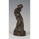 An early 20th century brown patinated cast bronze figure of a nude lady, leaning upon a rocky