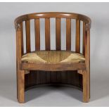 An Edwardian Arts and Crafts mahogany barrel back chair by Liberty & Co, the curved upright comb