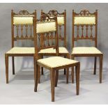 A set of four Edwardian Arts and Crafts oak framed dining chairs with pierced top rails and stylized