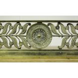 A Regency cast brass fender with central rosette flanked by curled laurel leaves and flowerheads,